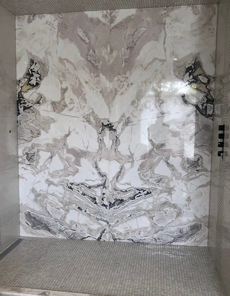 Book-matched shower wall above a mosaic tile floor